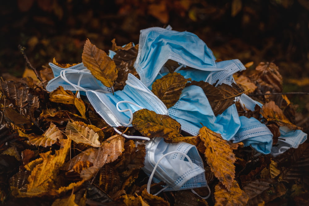 a pile of blue face masks on top of leaves