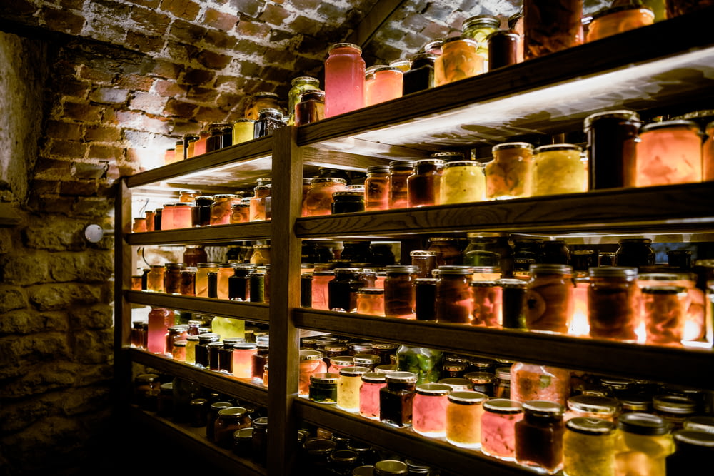 une étagère remplie de nombreux pots à côté d’un mur de briques