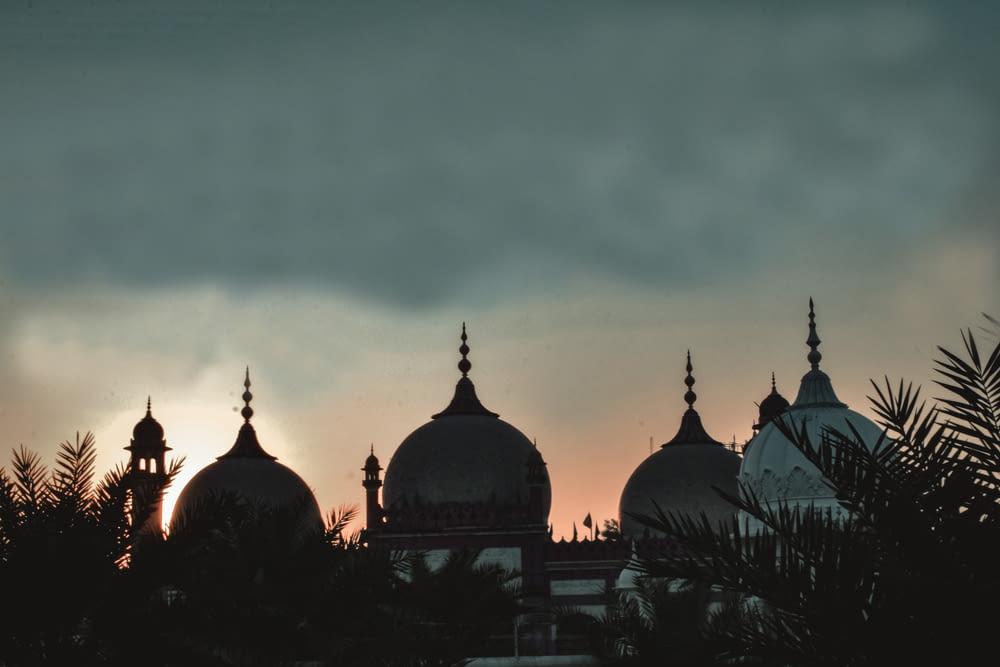 the sun is setting behind the domes of a building