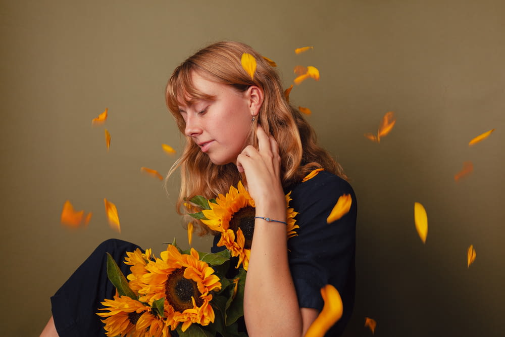 a woman holding a bouquet of sunflowers in front of her face