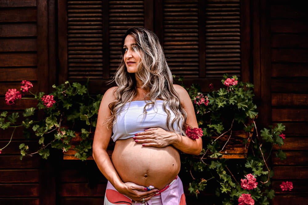 a pregnant woman standing in front of flowers