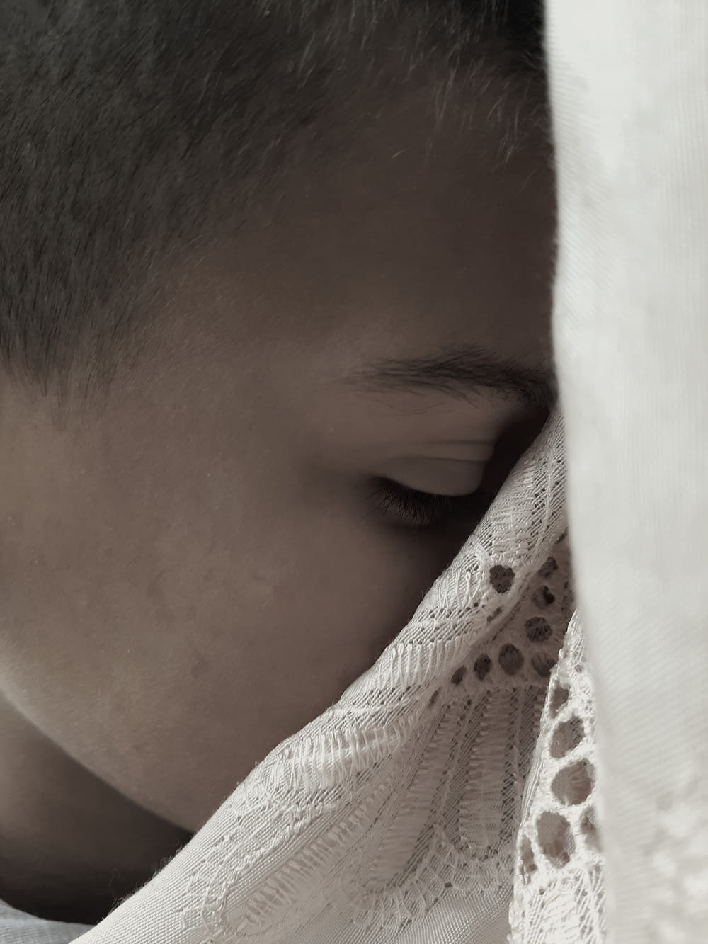 a young man covers his face with a white cloth
