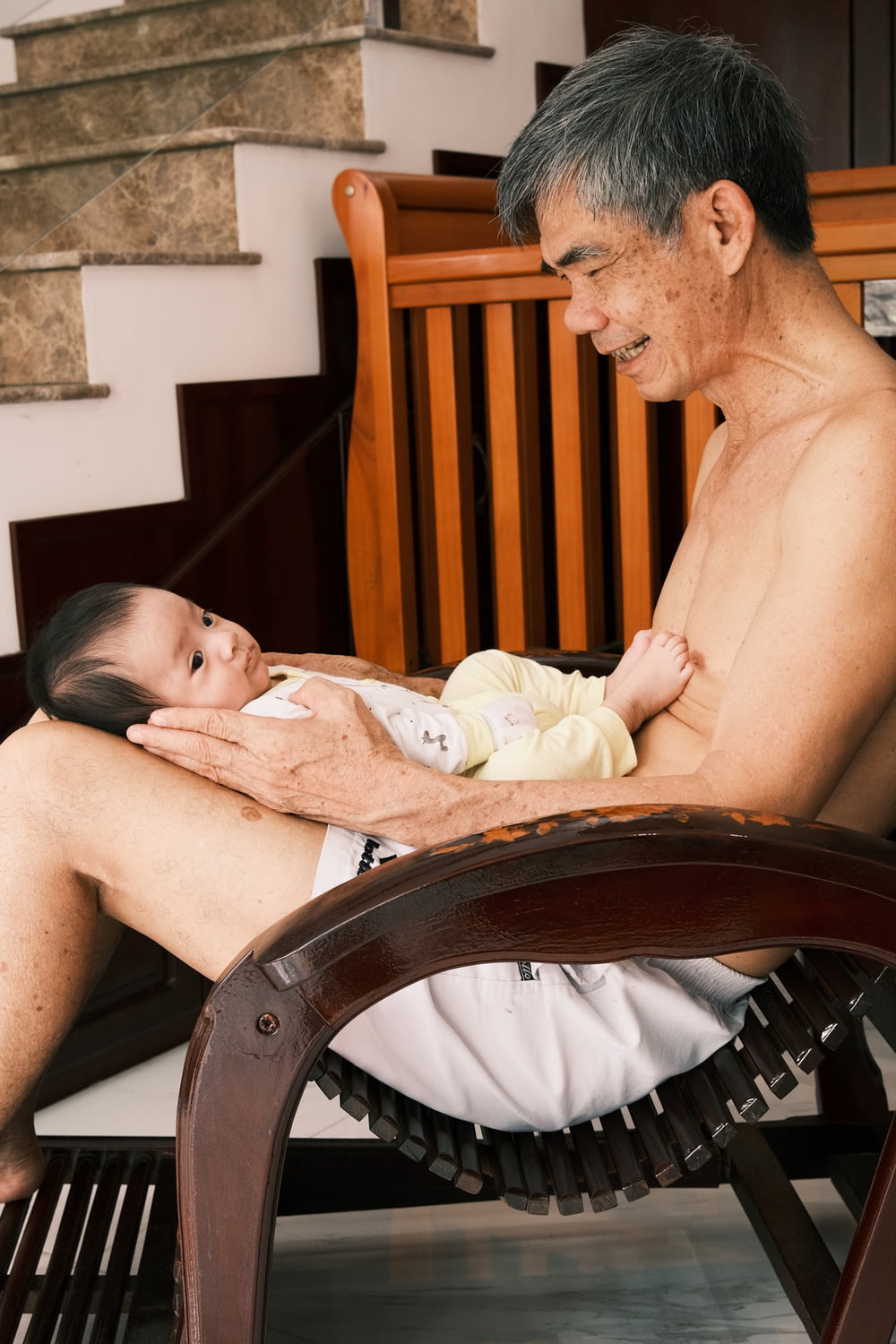 um homem sentado em uma cadeira segurando um bebê