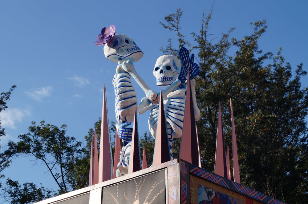 a couple of skeletons standing on top of a carnival ride