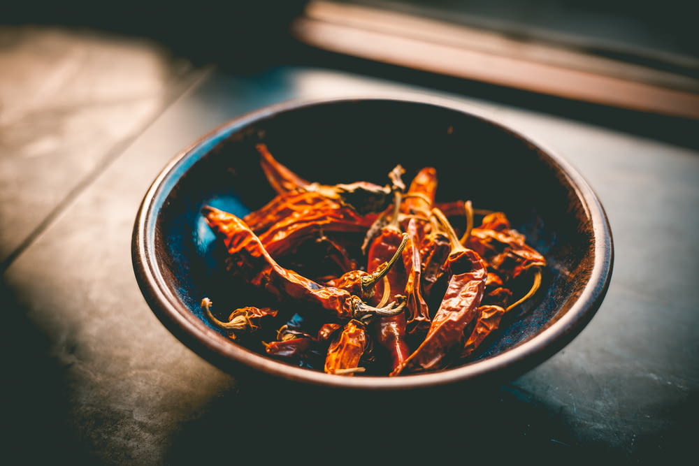 a bowl of dried red peppers on a table