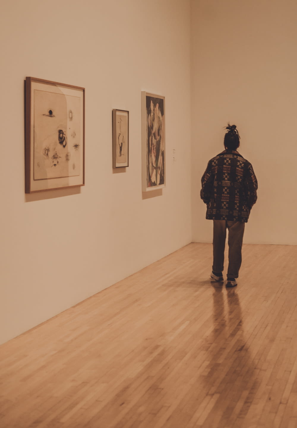 a person standing in a room with paintings on the wall