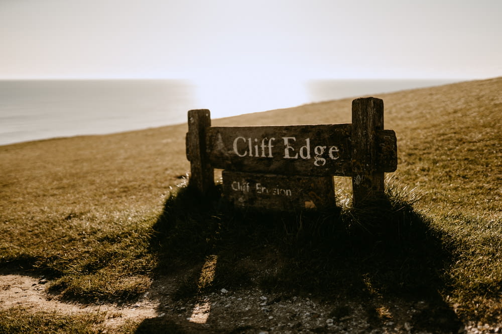 a wooden sign sitting on top of a lush green hillside