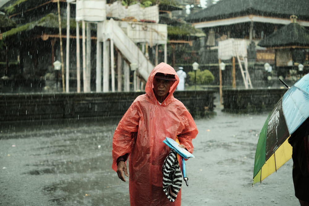 a man in a red raincoat holding an umbrella