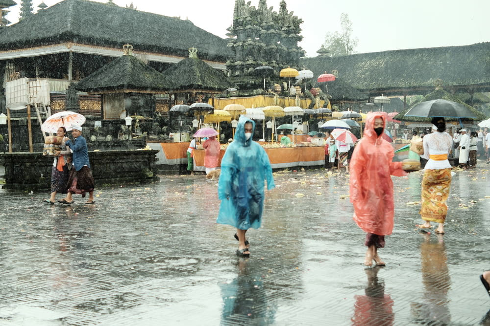 a group of people walking in the rain with umbrellas