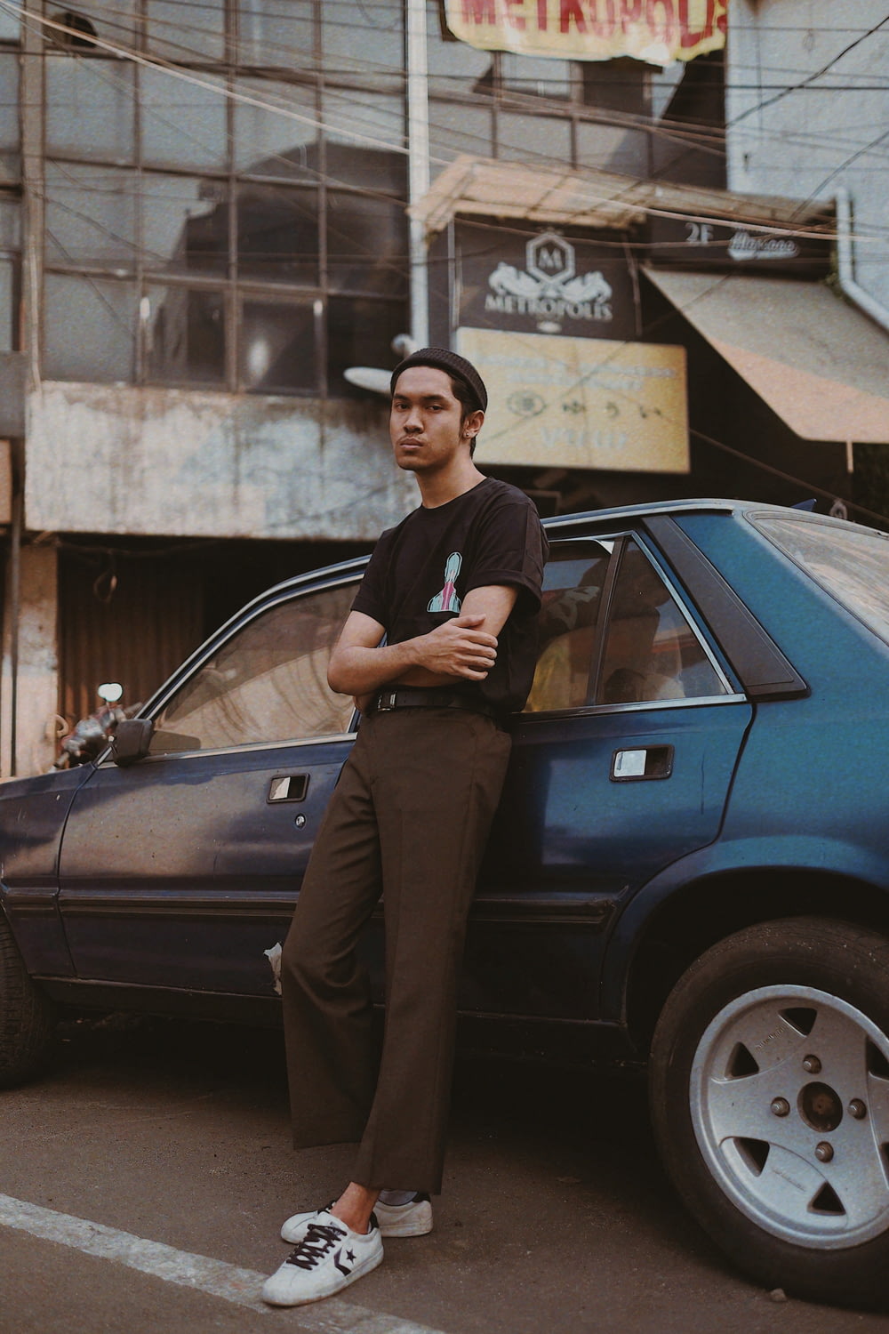 a man leaning on a car in front of a building