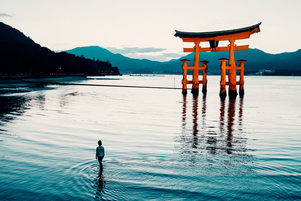 a person standing in the water in front of a floating tori tori