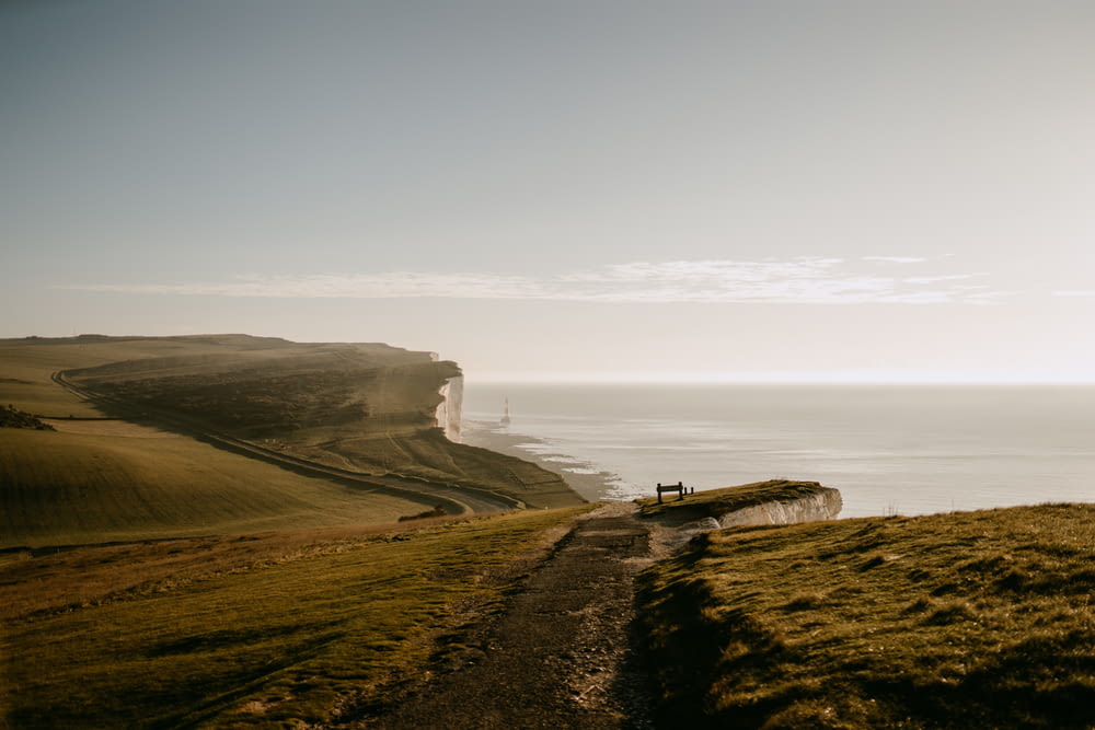 a person sitting on a bench on a hill overlooking the ocean