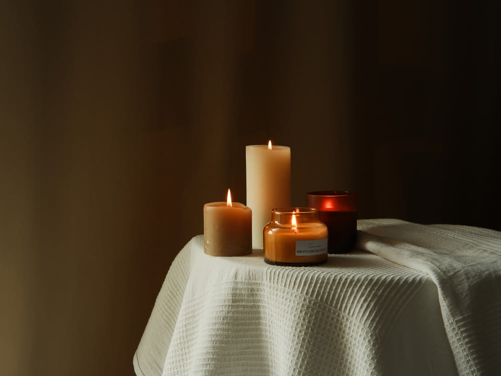 three lit candles sitting on a white table cloth