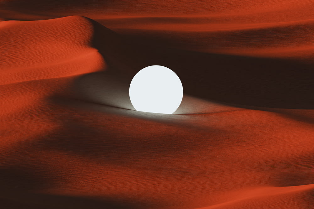 a white ball sitting in the middle of a desert