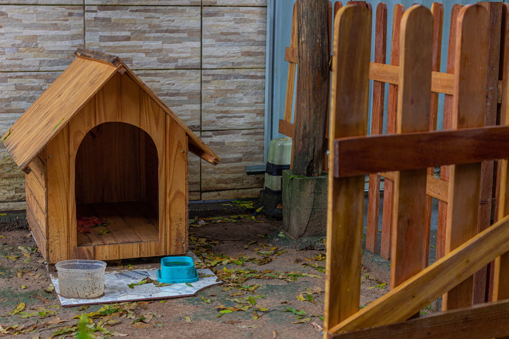 a wooden dog house with a bucket of water next to it