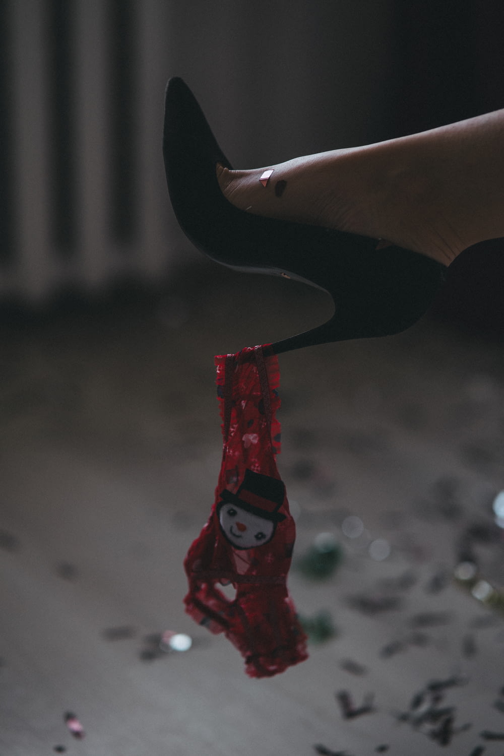 a woman's feet with a red shoe hanging from a string