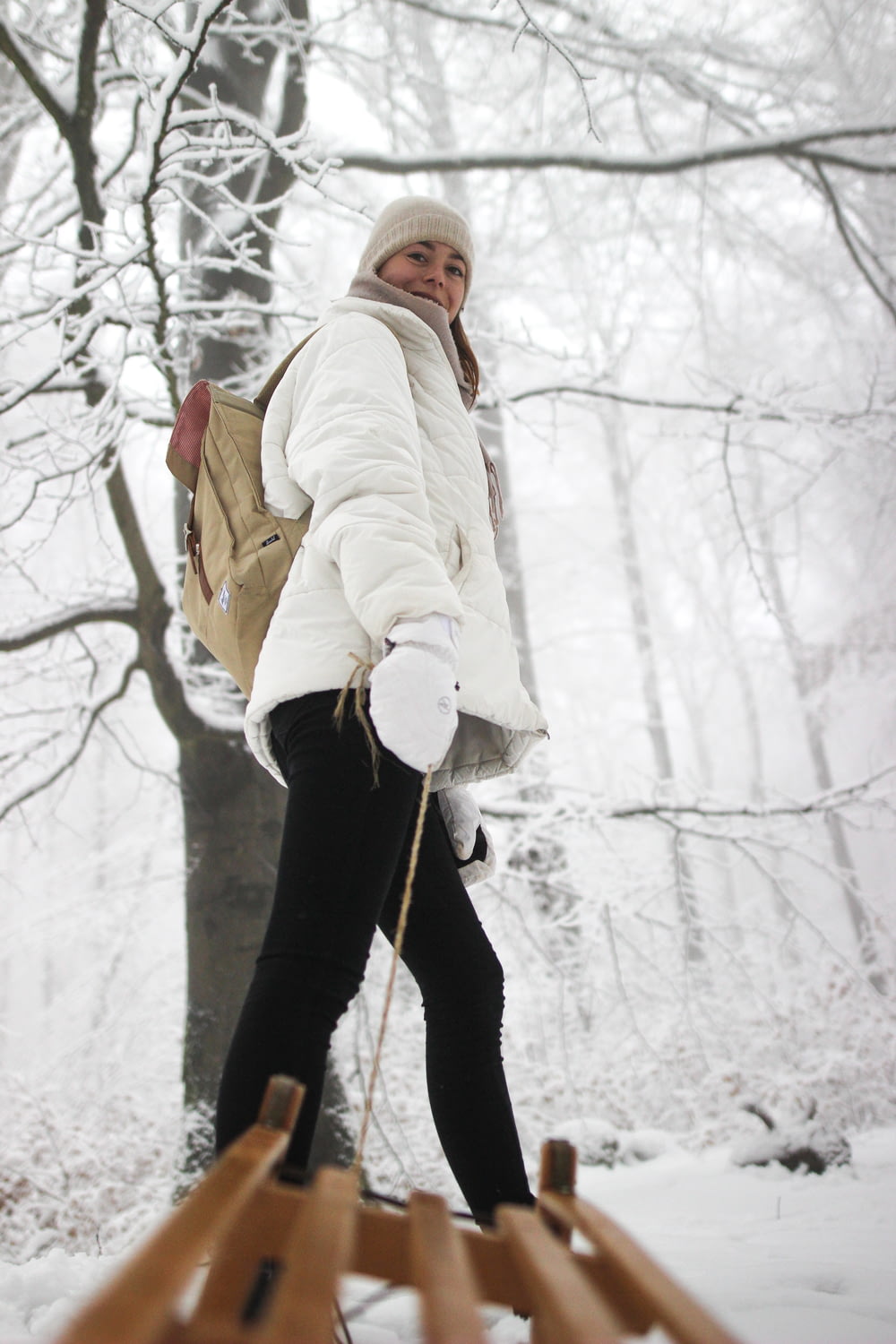 a woman walking across a snow covered forest
