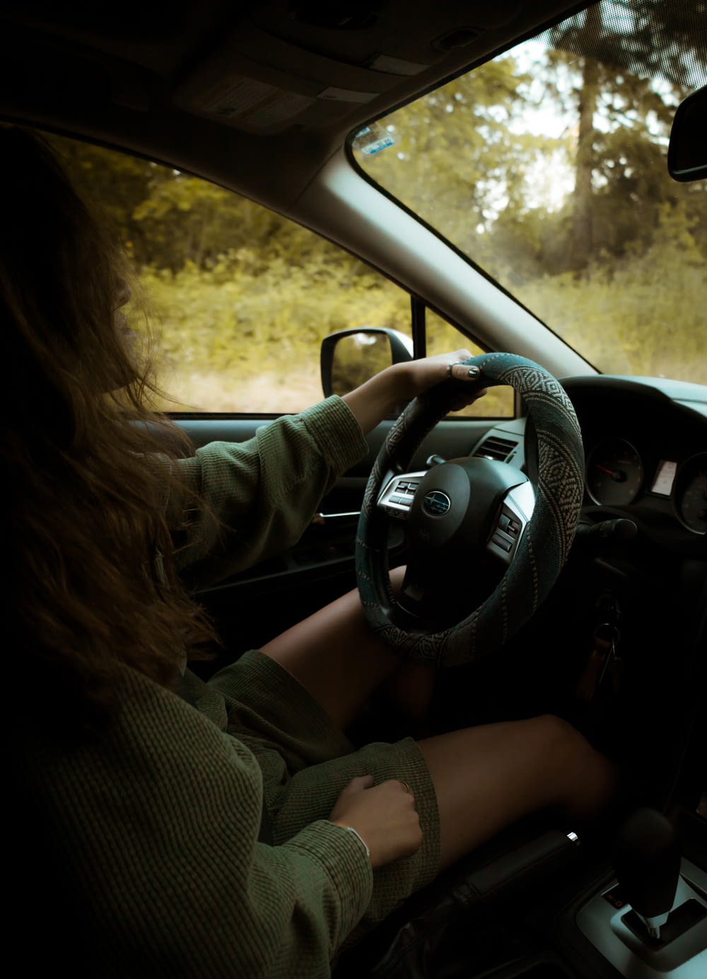a woman driving a car with a steering wheel