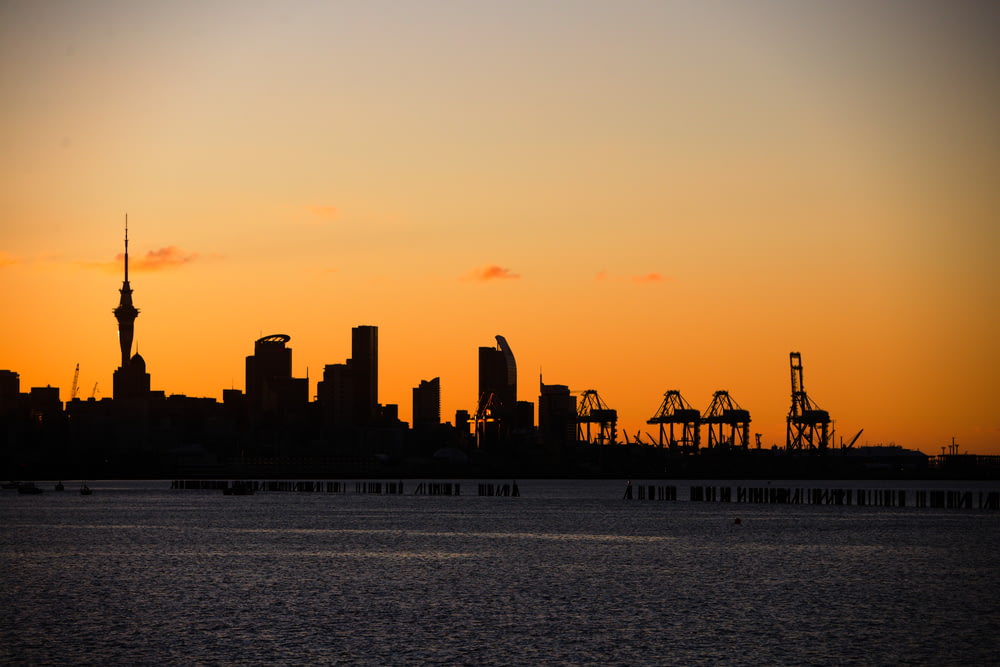 a city skyline at sunset with cranes in the foreground