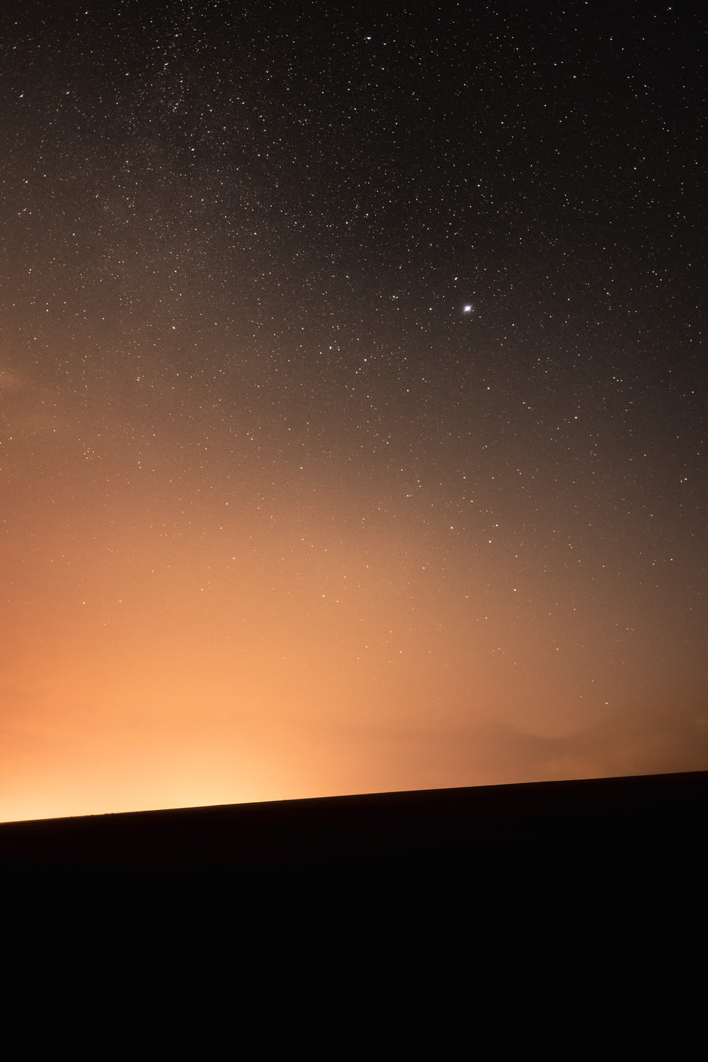 the night sky with stars and a bright orange glow