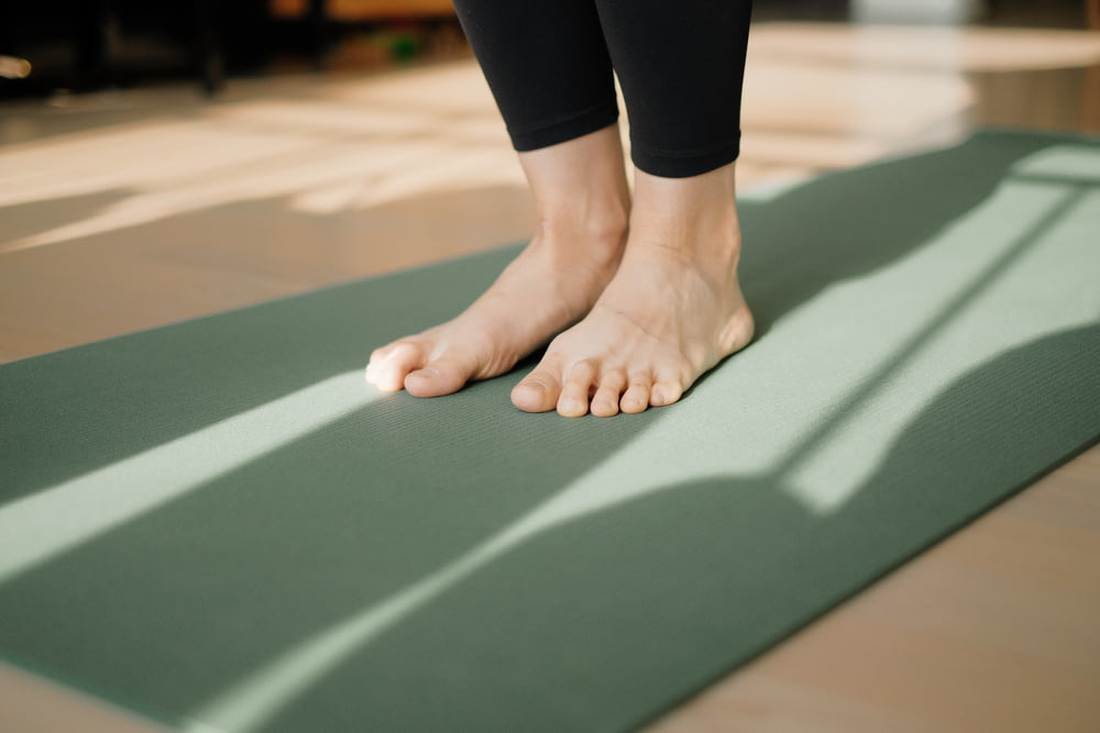 uma pessoa em pé em um tapete de yoga no chão