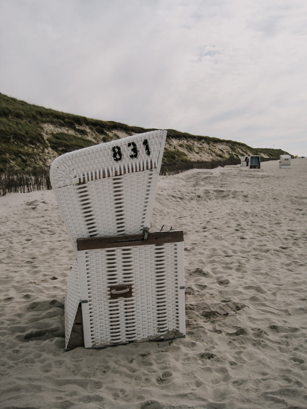 una sedia bianca seduta sulla cima di una spiaggia sabbiosa