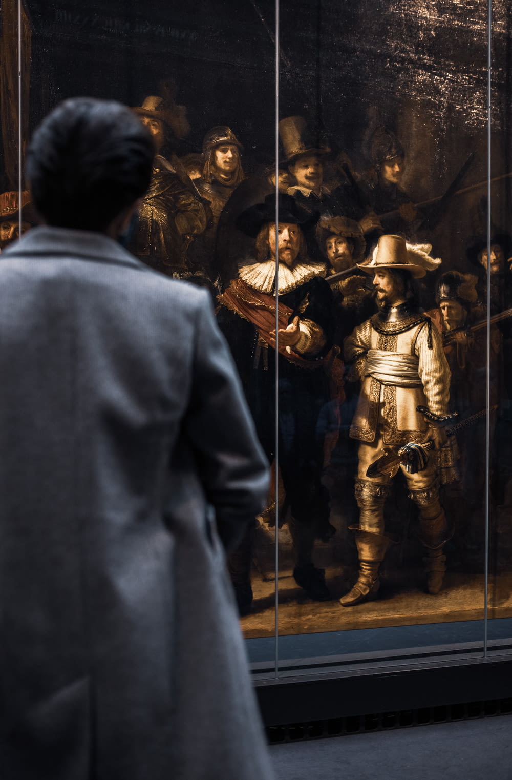 a man looking at a painting of a man in armor