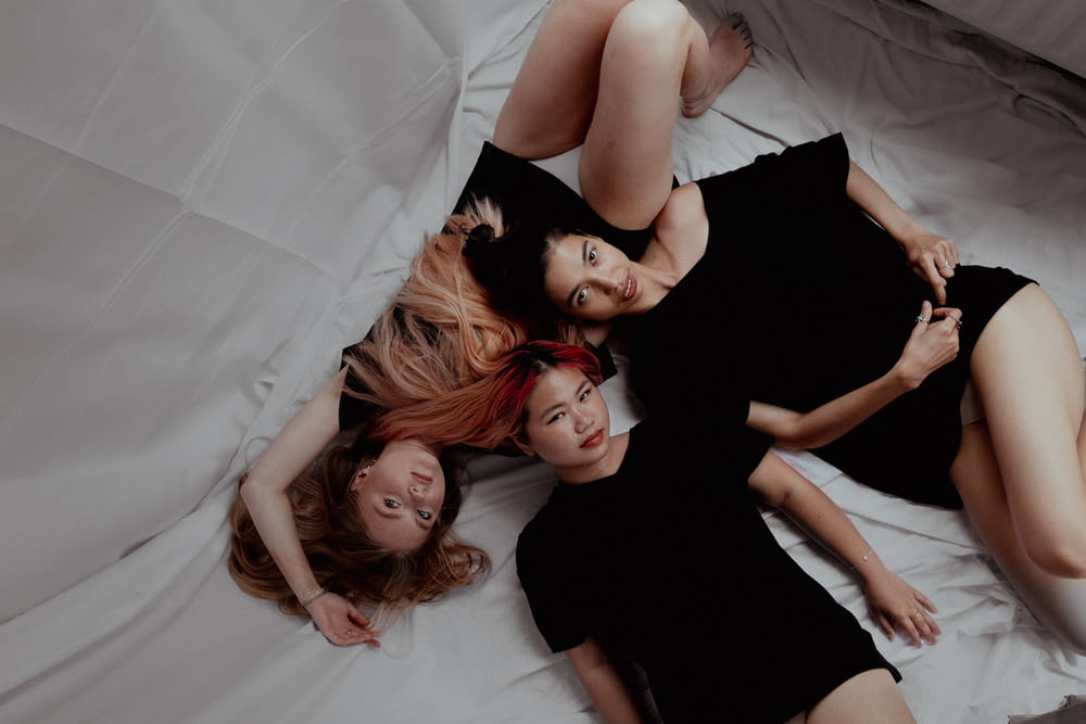 three women are laying on a bed together