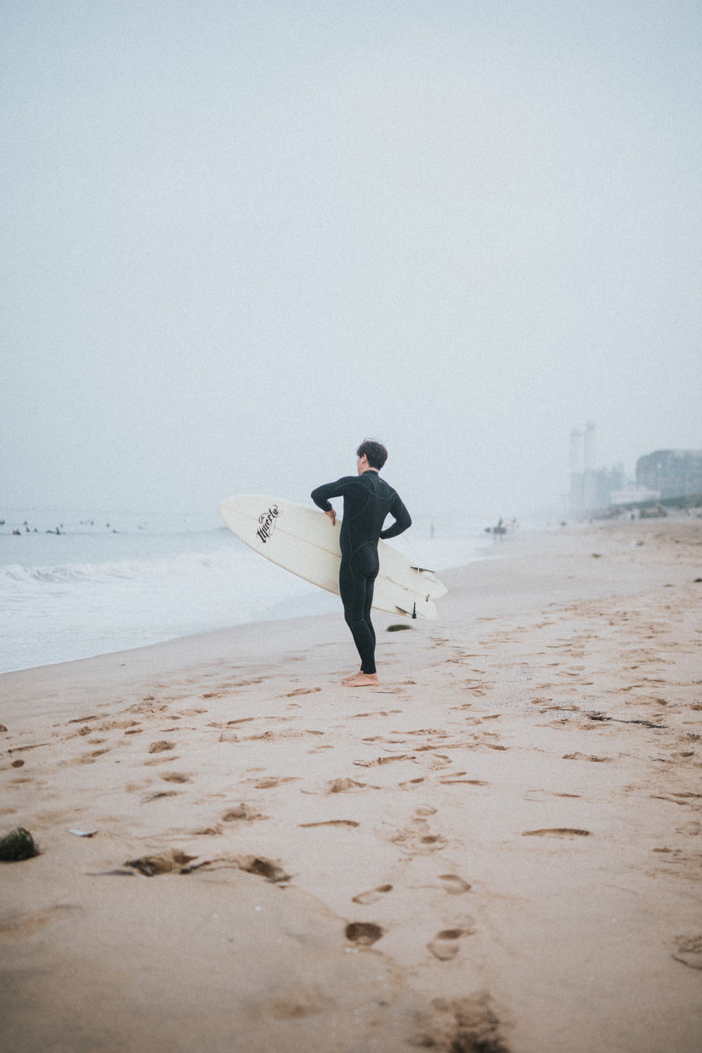 a man in a wet suit holding a surfboard on a beach