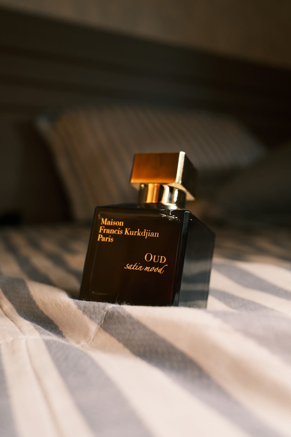 um frasco de perfume sentado em cima de uma cama