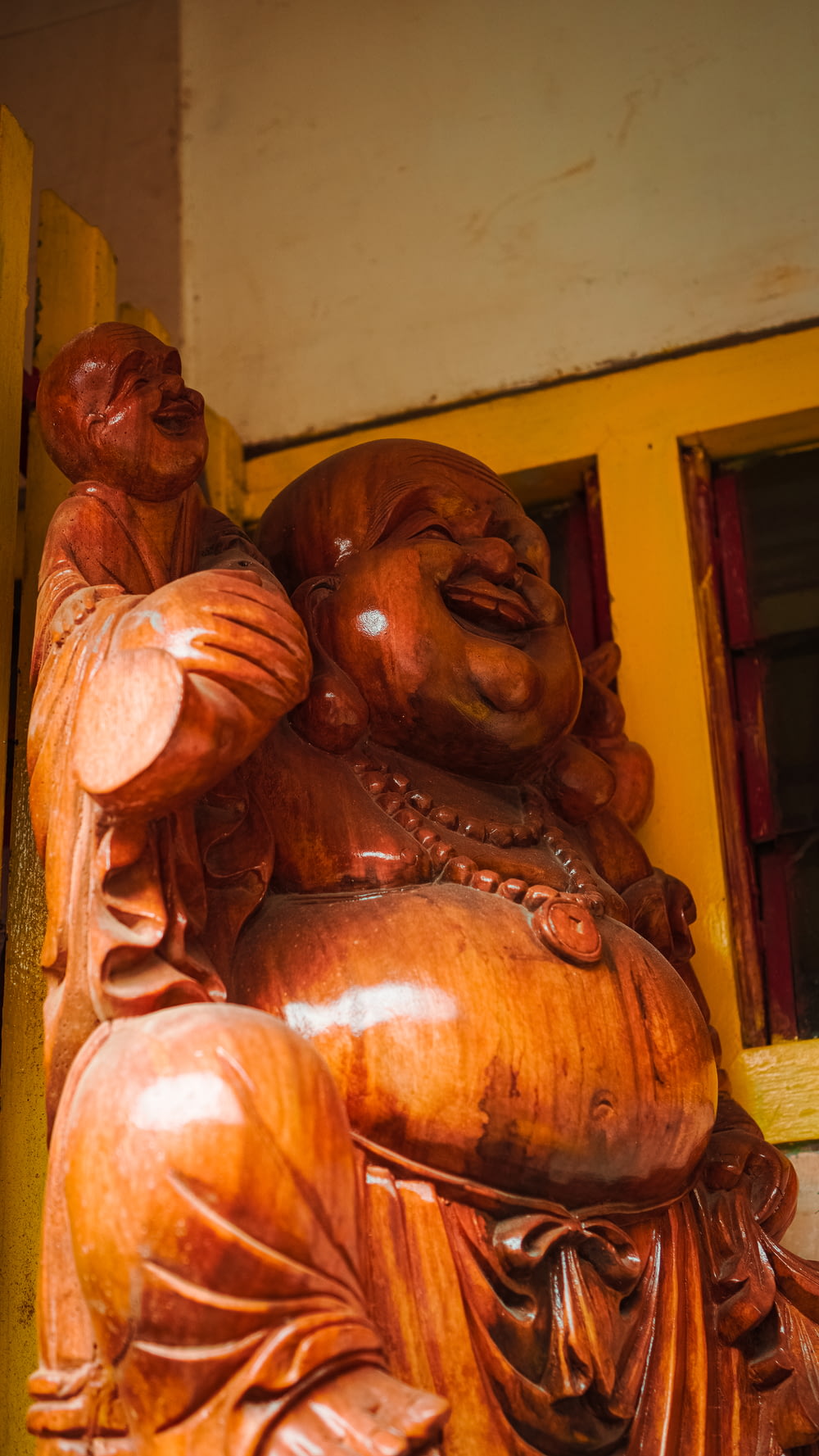 a wooden statue of a laughing buddha
