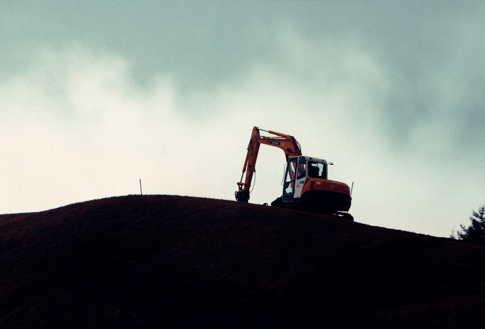 uma escavadeira no topo de uma colina em um dia nublado