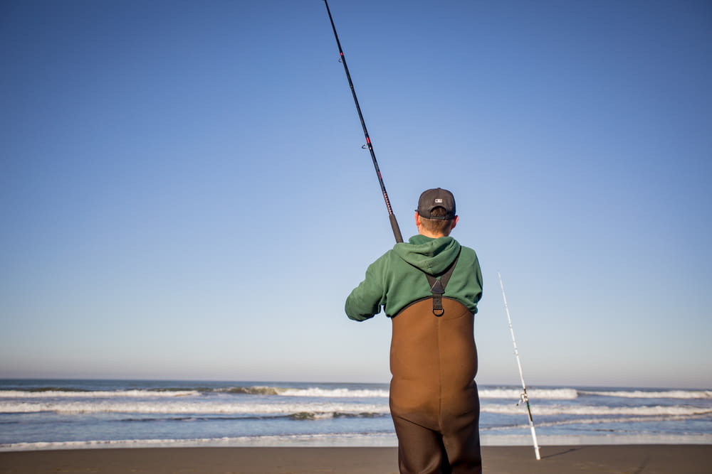 Un homme debout sur une plage tenant une canne à pêche