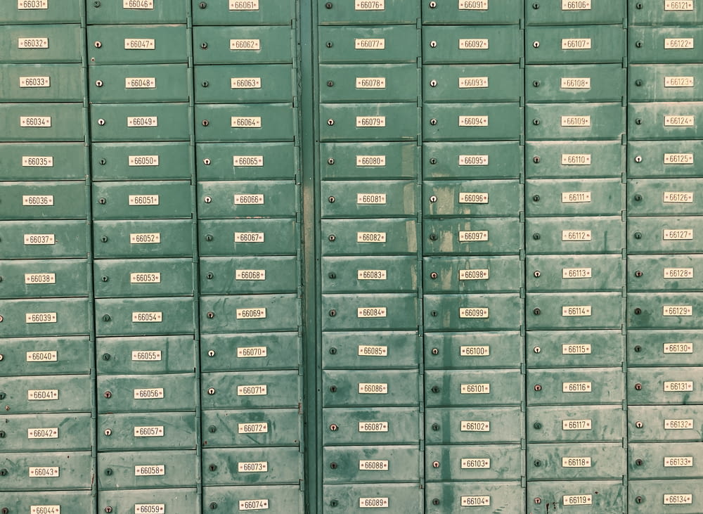 a row of green mail boxes with white labels on them