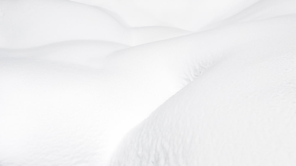 una cama cubierta de nieve con sábanas blancas y almohadas