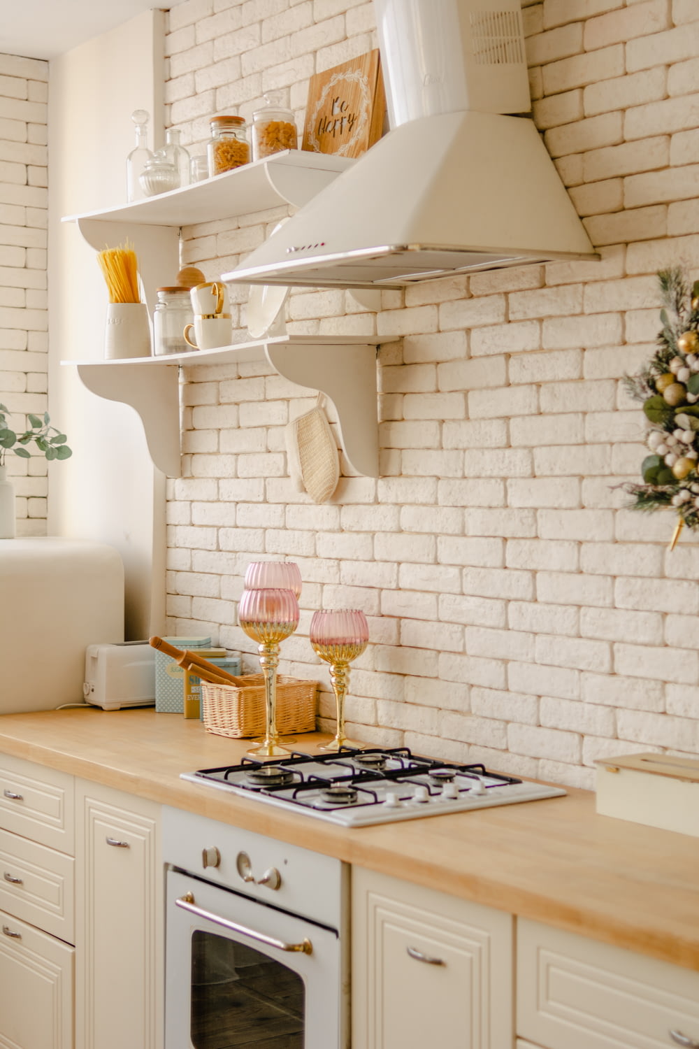 a kitchen with a stove top oven and a white brick wall