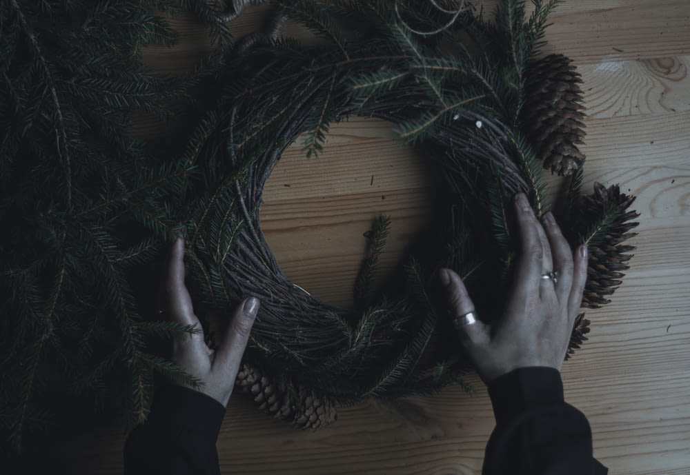a person holding a wreath on top of a wooden table
