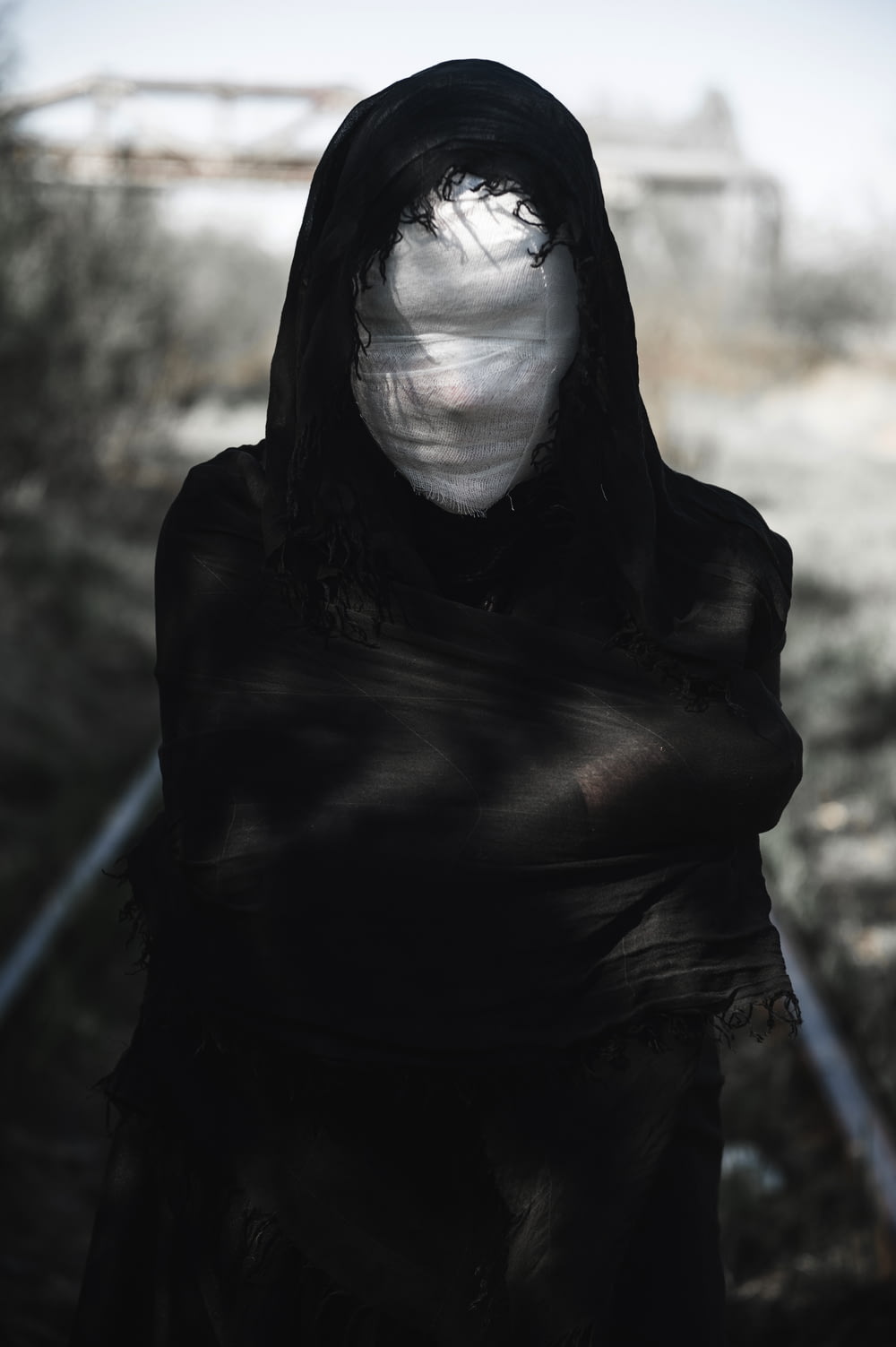 a person wearing a black hooded jacket and a white mask