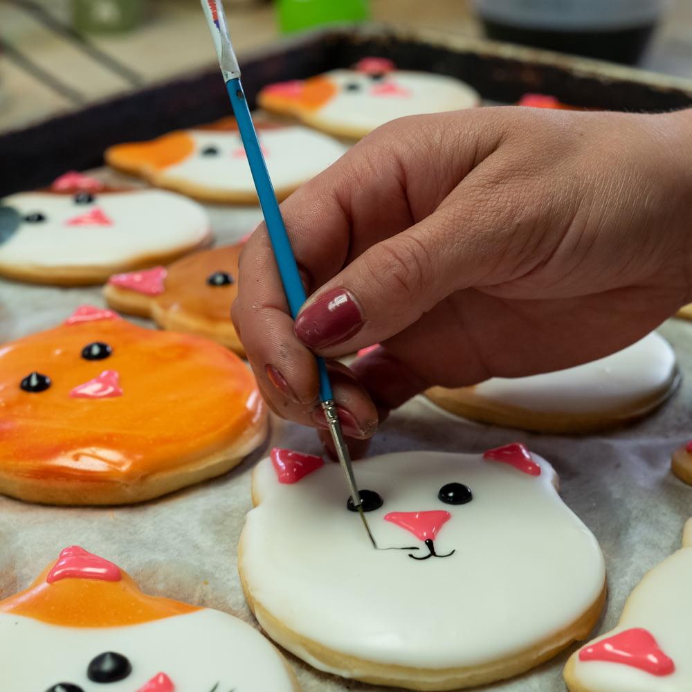 a person with a pencil in their hand painting decorated cookies