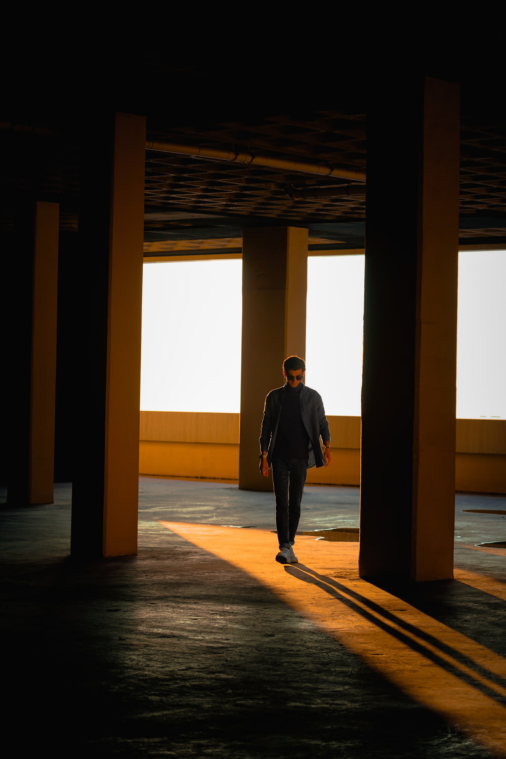 a man in a suit walking through a parking garage