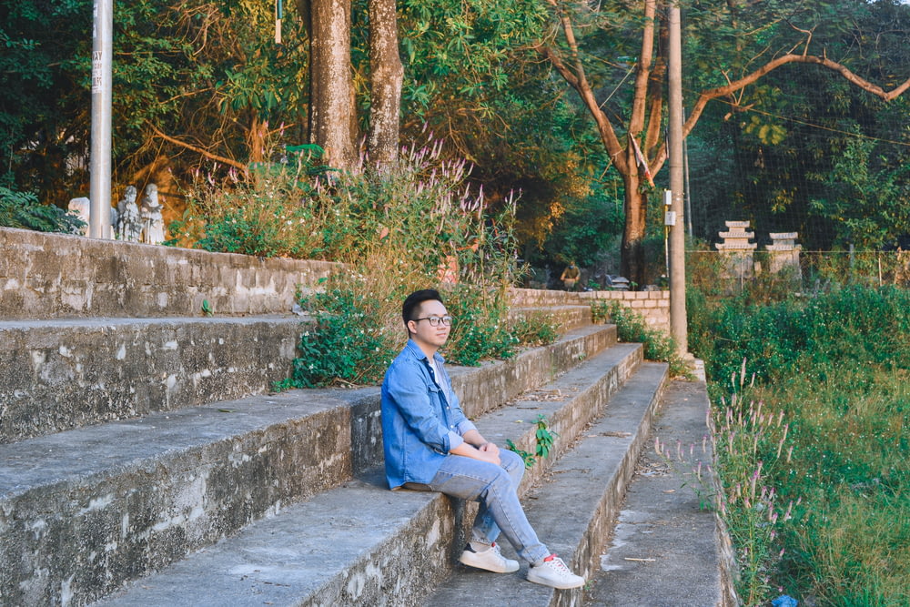 a man sitting on a stone step next to a forest