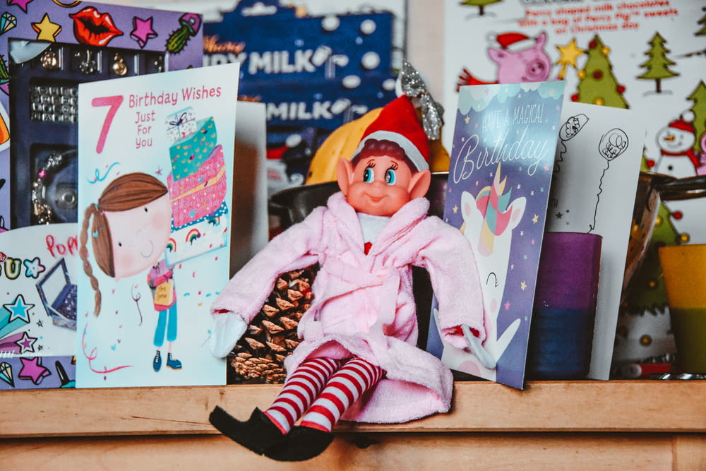 a elf doll sitting on top of a shelf filled with books