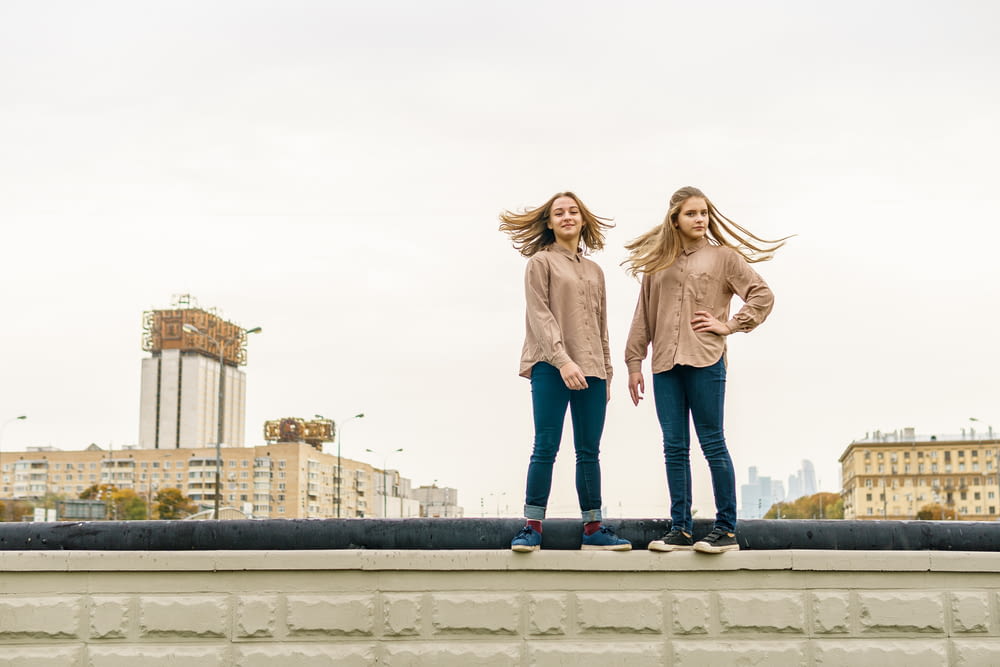two women standing on a ledge in front of a city