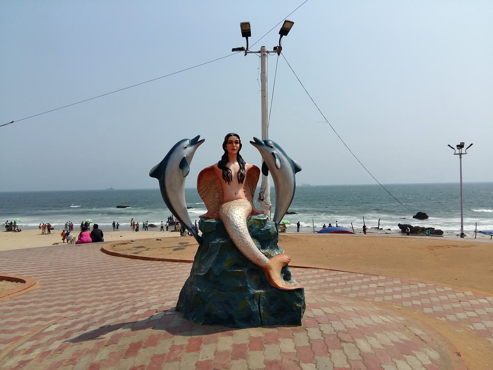Une statue d’une femme assise au sommet d’un dauphin