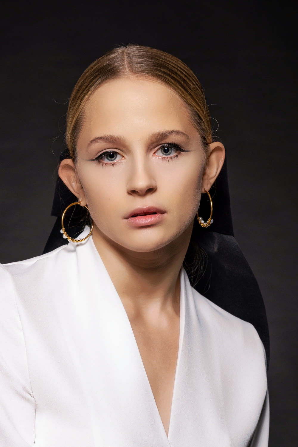 a woman in a white shirt and gold hoop earrings