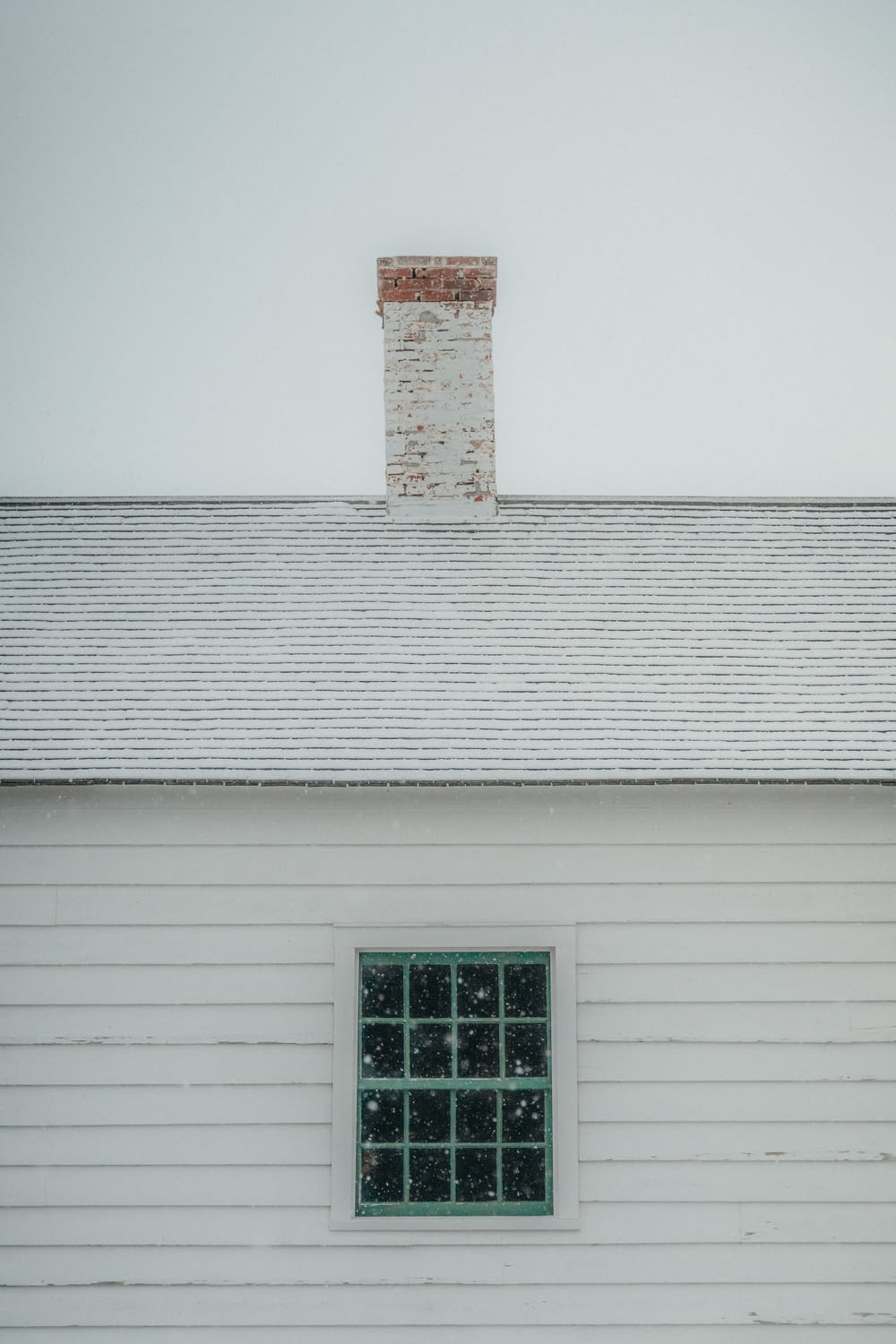 a white building with a window and a brick chimney