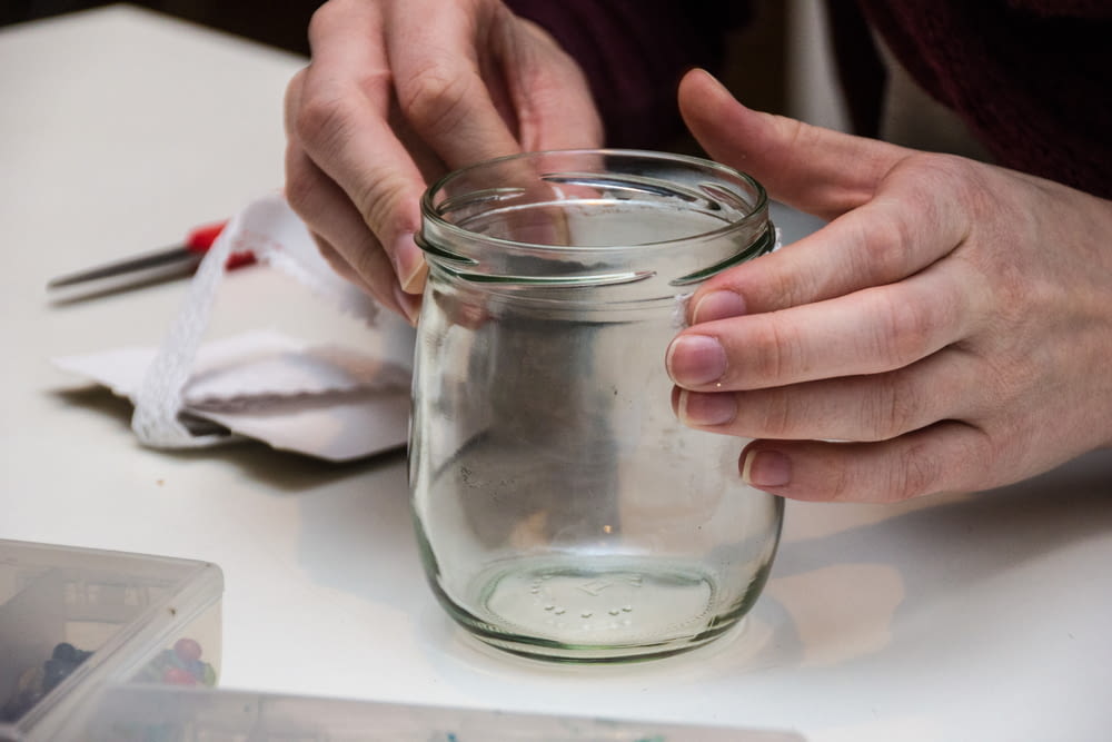 a person holding a glass jar on a table
