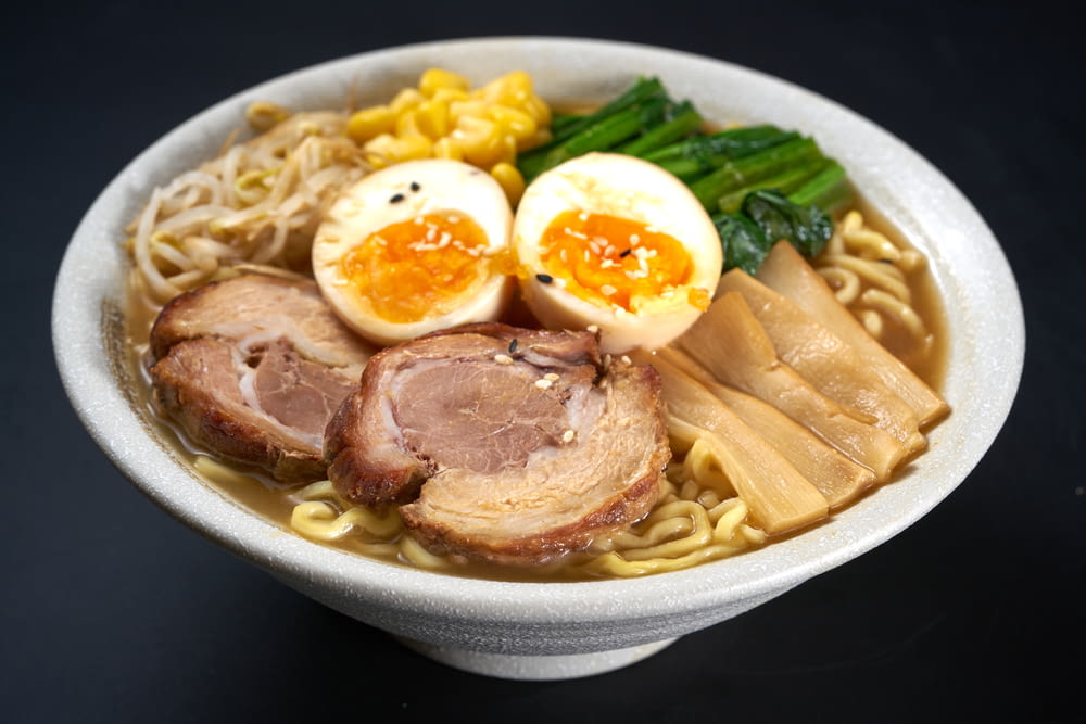 a bowl of ramen with meat, eggs, noodles and vegetables