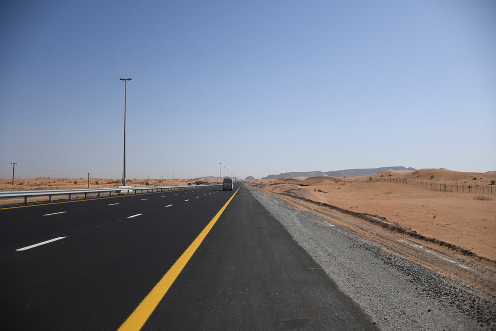 a highway with a car driving on it in the middle of the desert