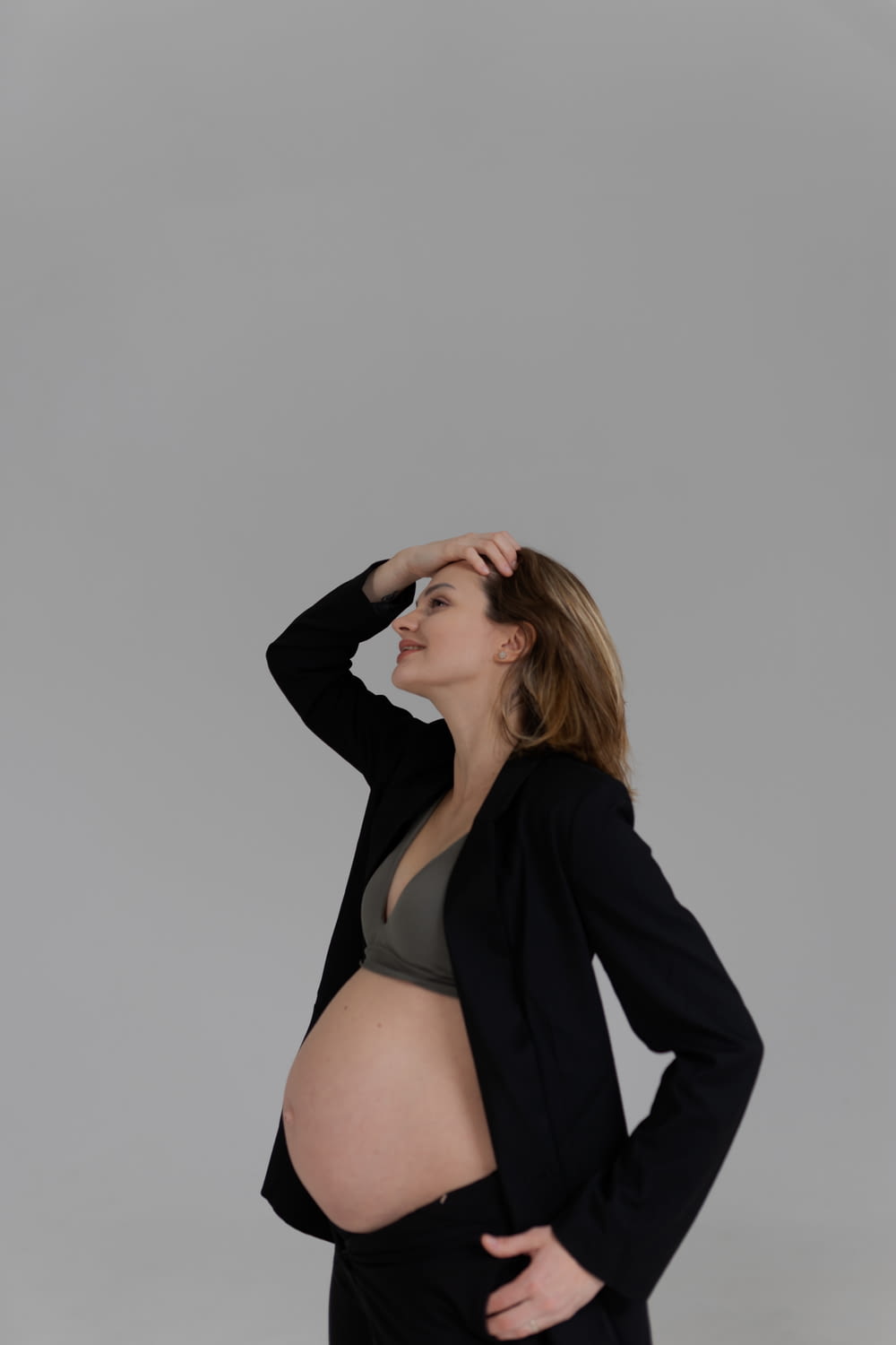 a pregnant woman in a black suit poses for a picture